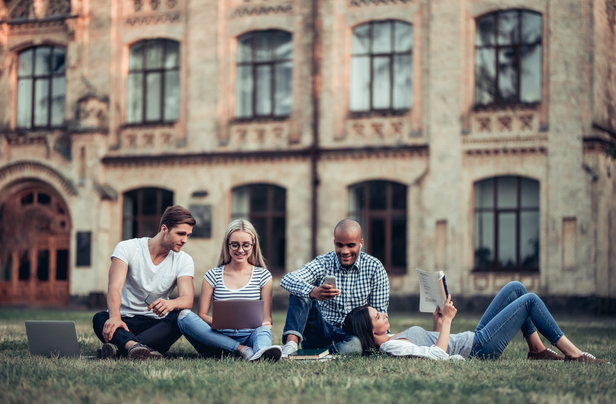 Students are sitting on the grass near university.